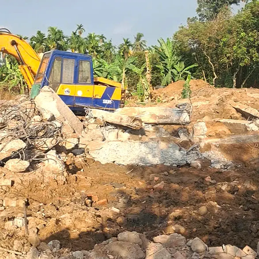 Máy xúc màu vàng xử lý kết cấu bê tông ngoài trời tại công trường Thuận An.